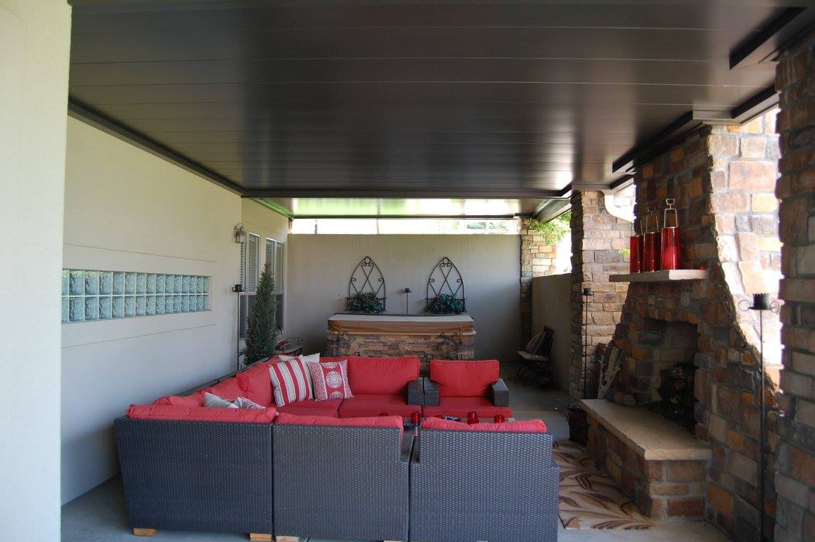 Finished outdoor living room with underdeck ceiling, stone fireplace, and lounge furniture