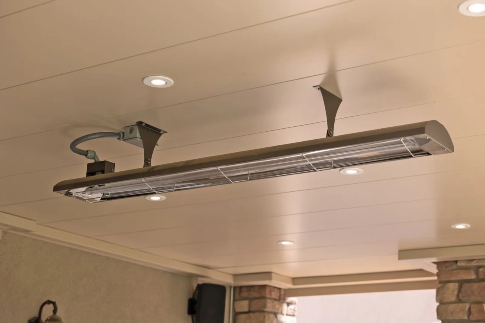 Ceiling-mounted electric quartz infrared heater bar with recessed can lights on an Undercover Systems underdeck ceiling