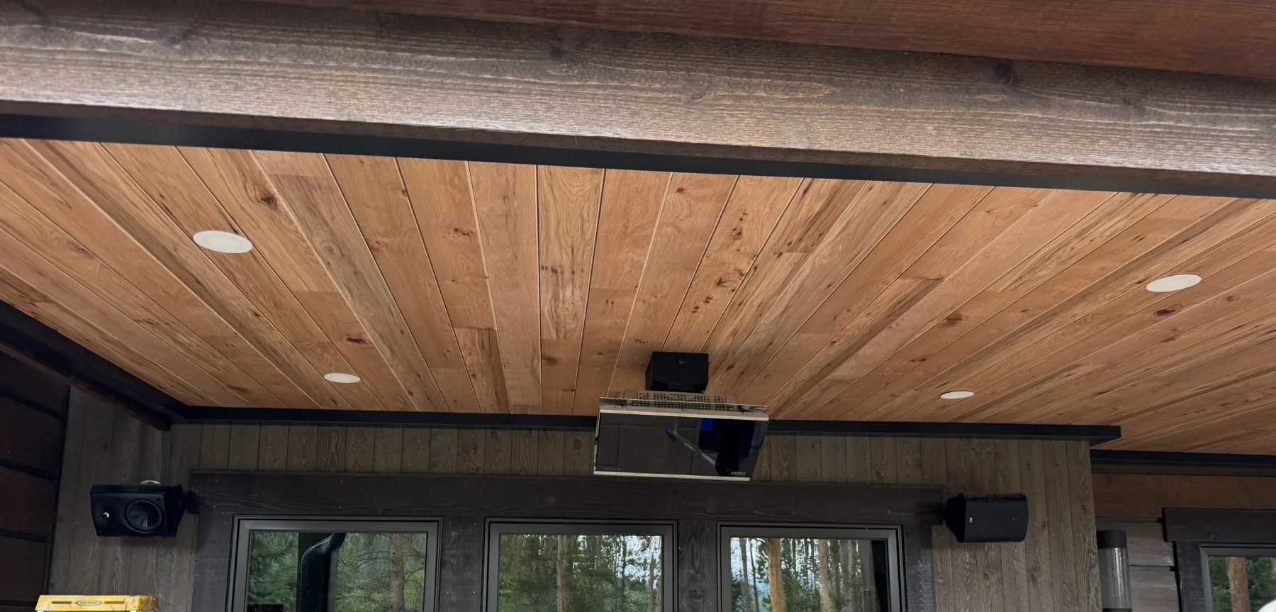Wood-finish underdeck ceiling with recessed lighting, projector, and integrated speakers