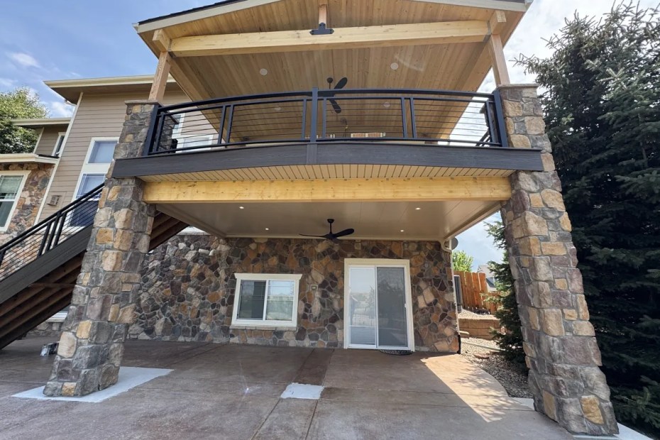Finished underdeck ceiling system with wood ceiling and stone columns on a Castle Rock, CO home