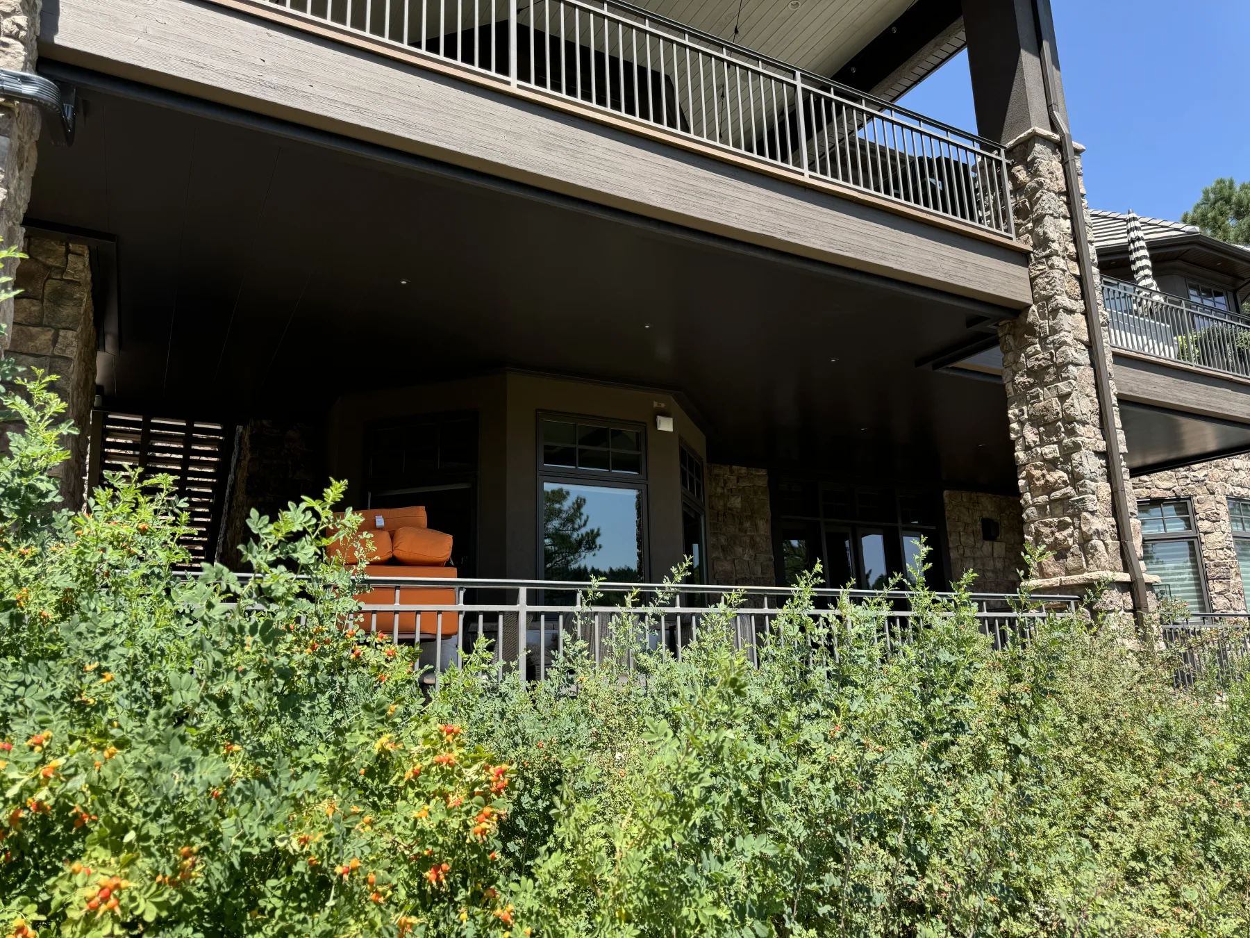 Dark finished underdeck ceiling panels seen from the yard, with a walkout patio beneath the upper deck
